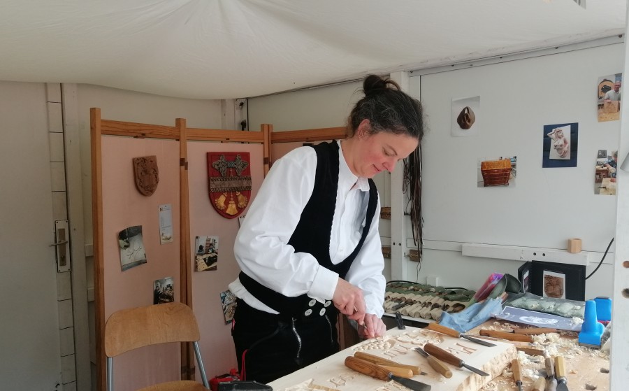 Astrid schnitzt beim Wienliebe Festival in der Zunftkleidung der Tischler und Holzgestalter
